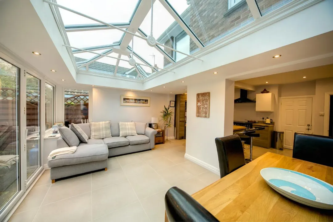 Edwardian conservatory with a glazed roof, white frames, open-plan lounge and kitchen dining area.