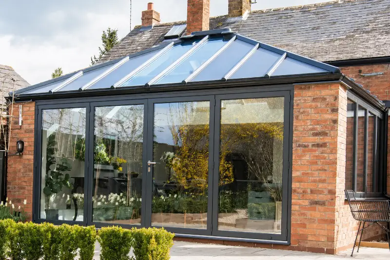 Livinroof conservatory roof replacement on a brick property showing solid insulated panels combined with full-width glazed sections and anthracite grey aluminium frames