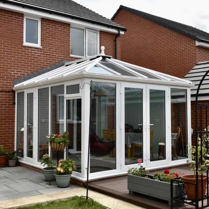 White framed Edwardian conservatory with glazed roof, double doors and garden patio area.